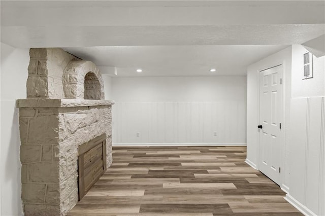 5547 Rockhill Rd, Kansas City, MO 64110 - below grade area with baseboards, a wainscoted wall, wood finished floors, and a fireplace