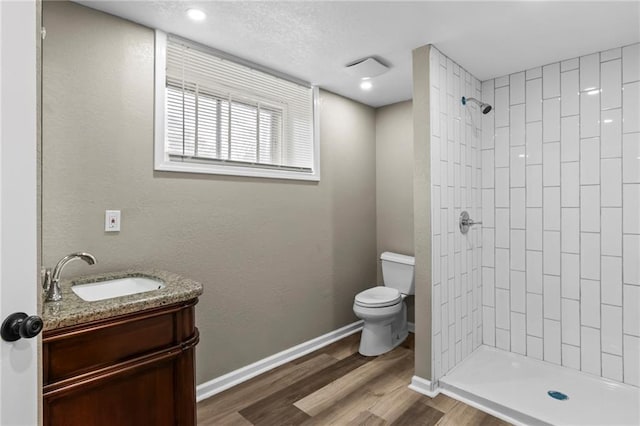 5547 Rockhill Rd, Kansas City, MO 64110 - bathroom featuring tiled shower, wood finished floors, vanity, and toilet