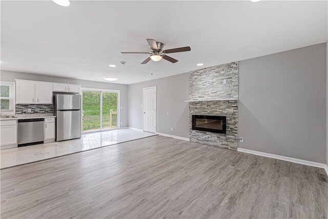 709 W 28th St N, Independence, MO 64050 - unfurnished living room with light wood-style flooring, baseboards, recessed lighting, ceiling fan, and a fireplace