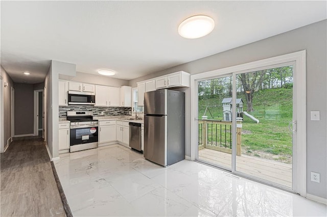 709 W 28th St N, Independence, MO 64050 - kitchen featuring tasteful backsplash, baseboards, white cabinetry, light countertops, and appliances with stainless steel finishes