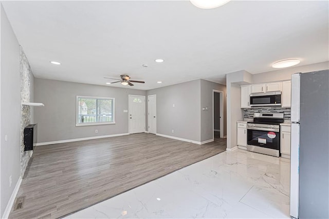 709 W 28th St N, Independence, MO 64050 - kitchen with stainless steel appliances, baseboards, recessed lighting, white cabinetry, and a ceiling fan