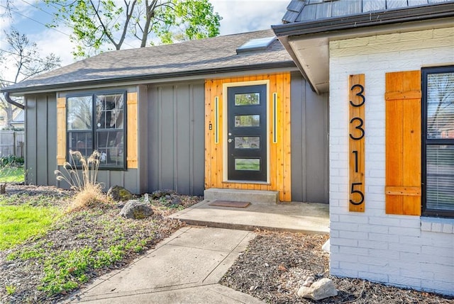 entrance to property with board and batten siding and a shingled roof