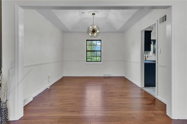 unfurnished dining area with a chandelier, a raised ceiling, ornamental molding, and wood-type flooring