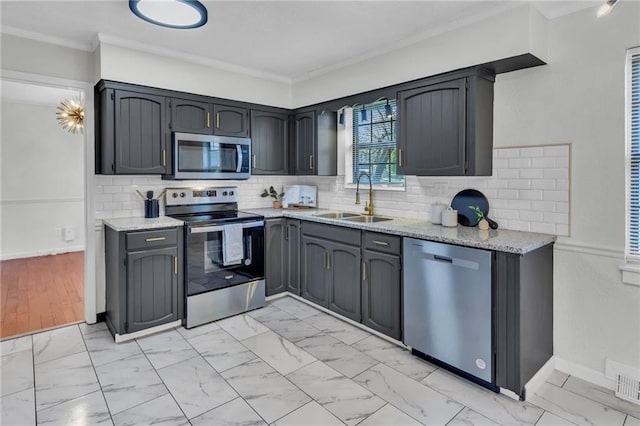 kitchen with light stone counters, a sink, appliances with stainless steel finishes, ornamental molding, and marble finish floor