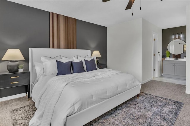 carpeted bedroom with baseboards, ceiling fan, connected bathroom, and a sink