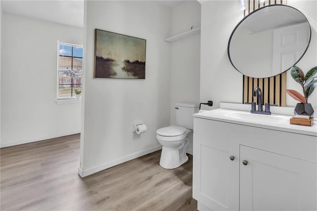 bathroom featuring baseboards, wood finished floors, and toilet