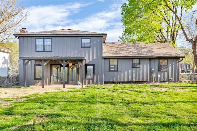 rear view of property with a lawn, a chimney, board and batten siding, and a fenced backyard
