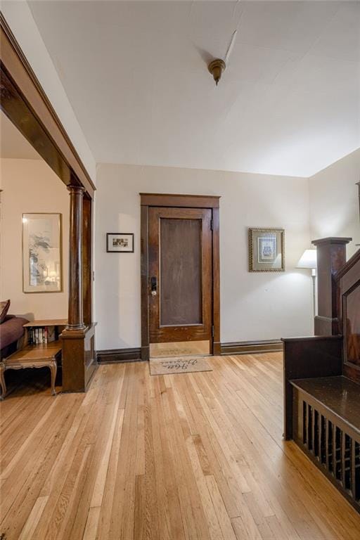 hall featuring light wood-style floors and ornate columns