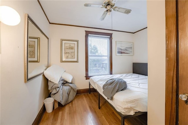 bedroom with ceiling fan, wood finished floors, baseboards, and ornamental molding