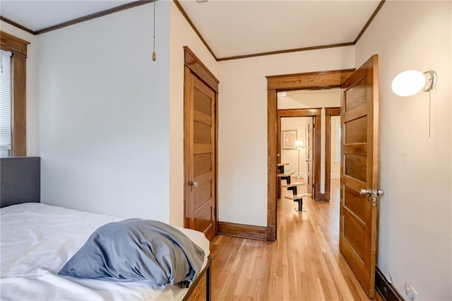 bedroom featuring light wood-style floors, crown molding, and baseboards