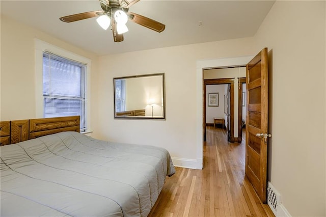 bedroom with light wood-style flooring, a ceiling fan, and baseboards
