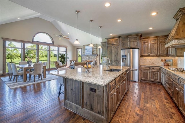 18670 W 248th St, Paola, KS 66071 - kitchen featuring stainless steel appliances, a sink, a breakfast bar area, custom exhaust hood, and light stone countertops