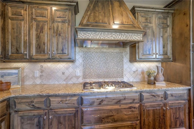 18670 W 248th St, Paola, KS 66071 - kitchen featuring custom range hood, stainless steel gas stovetop, backsplash, and light stone counters