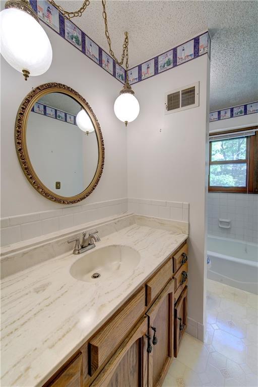 full bathroom with vanity, a textured ceiling, tile patterned flooring, and a tub