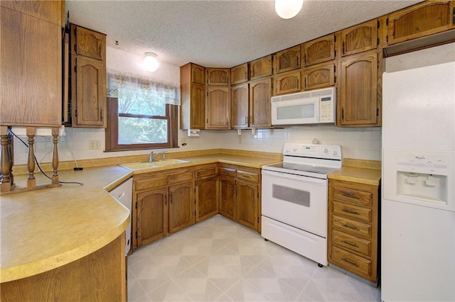 kitchen with white appliances, a sink, a textured ceiling, brown cabinetry, and light countertops