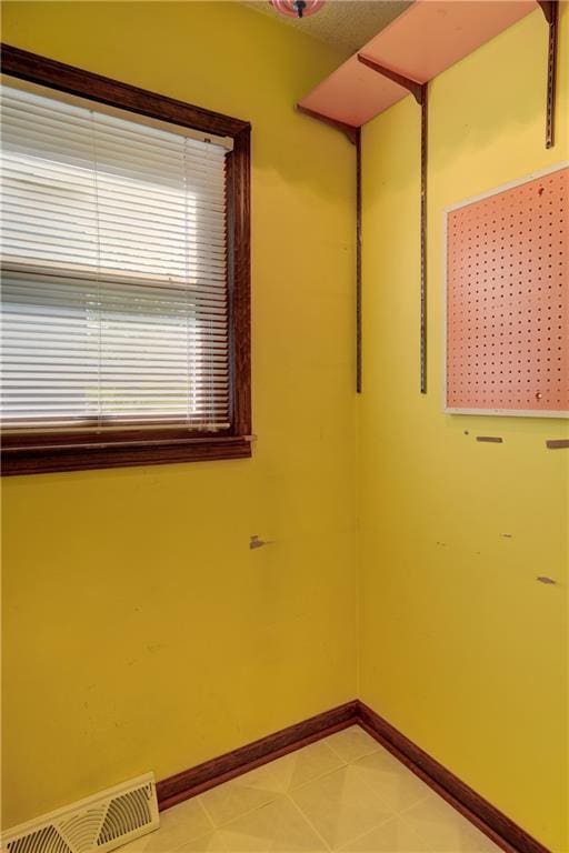 empty room featuring baseboards and light tile patterned floors