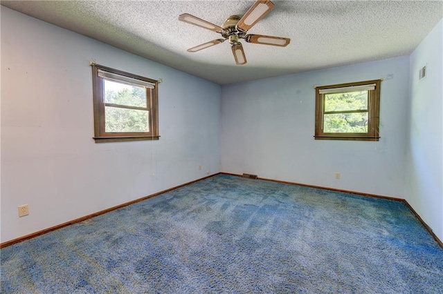 carpeted spare room featuring plenty of natural light, a ceiling fan, a textured ceiling, and baseboards