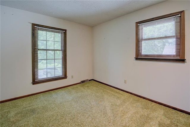 carpeted spare room featuring baseboards and a textured ceiling