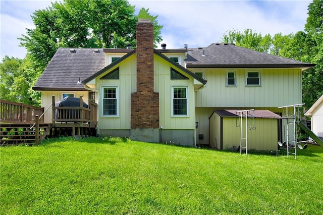 back of property featuring a wooden deck, a shed, a yard, an outdoor structure, and a chimney