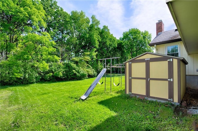 view of play area with a shed, a yard, an outbuilding, and view of scattered trees