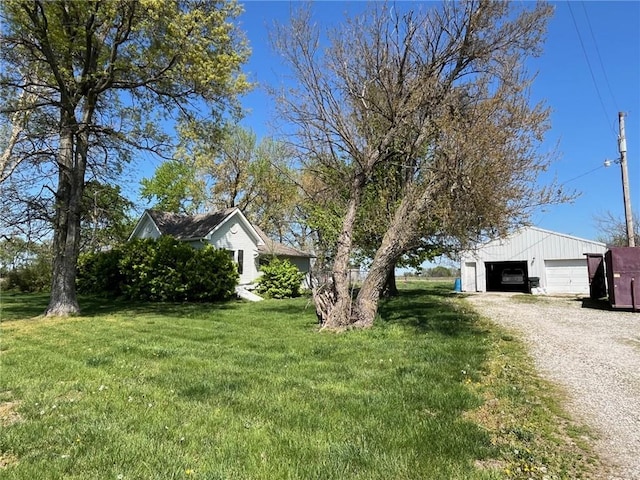 exterior space featuring a detached garage, an outbuilding, gravel driveway, and a front yard