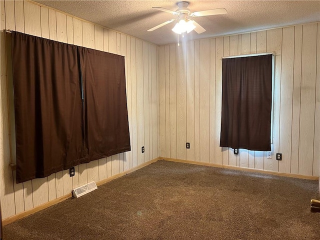 spare room featuring a ceiling fan, carpet flooring, wood walls, and a textured ceiling
