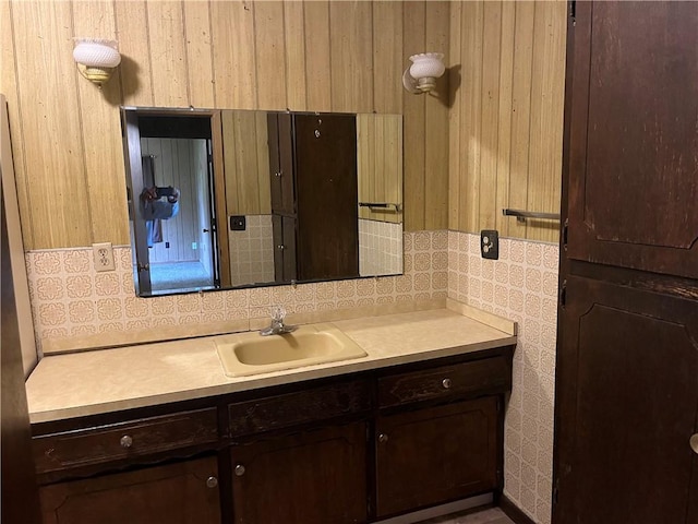 bathroom with vanity, wood walls, and tasteful backsplash