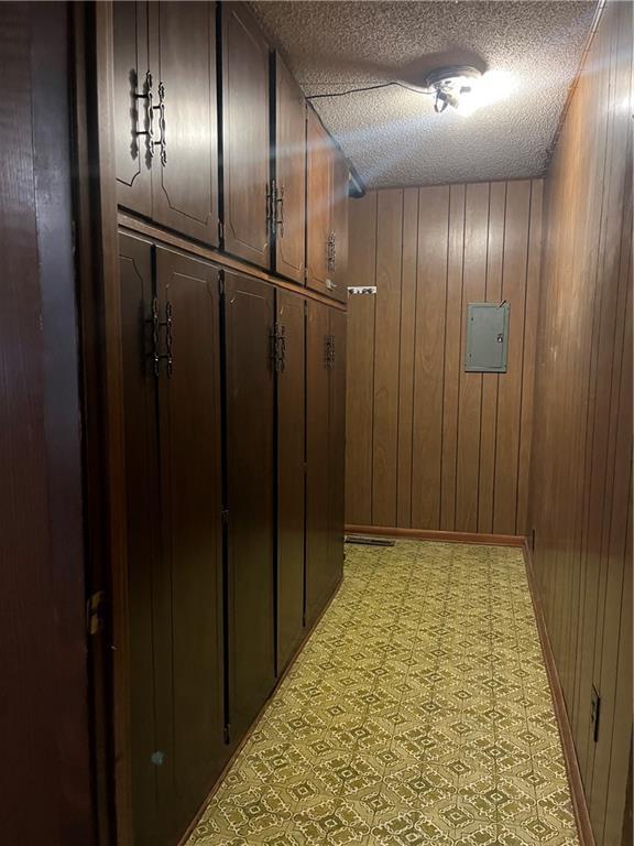 corridor featuring wood walls, light floors, and a textured ceiling