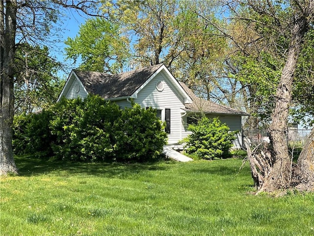 view of home's exterior with a lawn and a shingled roof