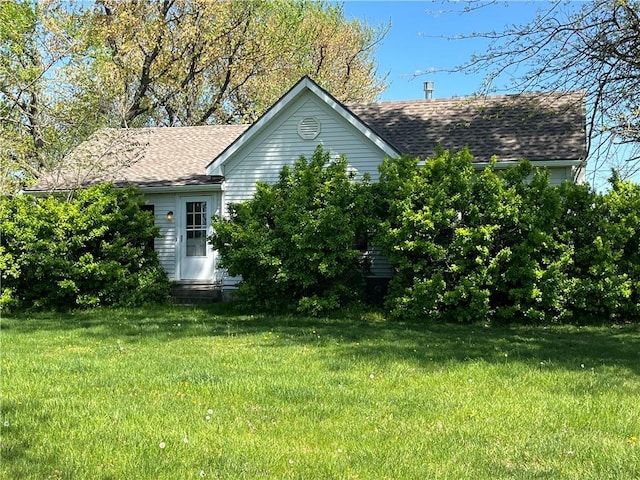 view of side of property with a lawn, a shingled roof, and entry steps