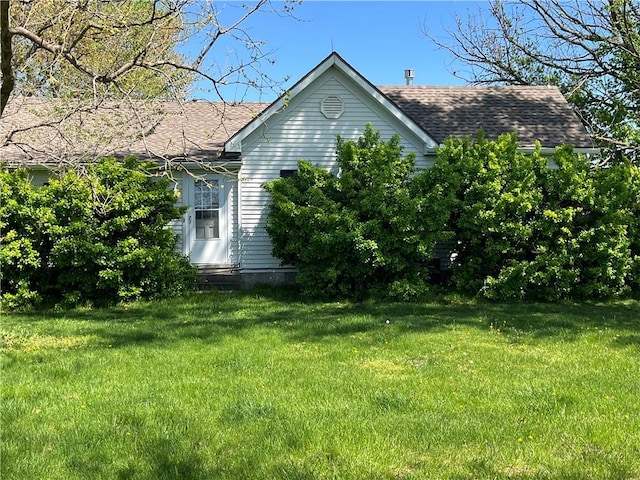 view of home's exterior with roof with shingles and a yard
