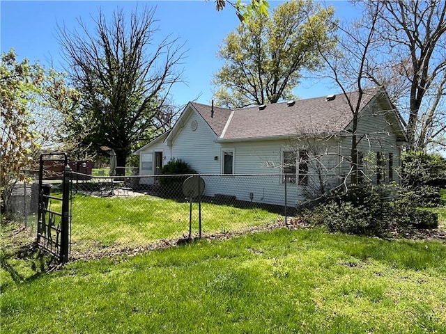 view of side of property featuring a lawn, fence, and roof with shingles