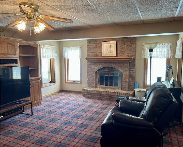 2317 Rhonda Rd, Excelsior Springs, MO 64024 - living room with carpet flooring, a brick fireplace, a ceiling fan, and baseboards