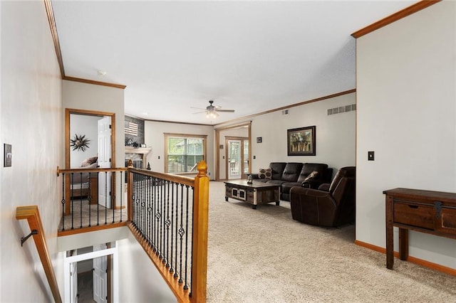 carpeted living room with visible vents, ornamental molding, baseboards, and a ceiling fan