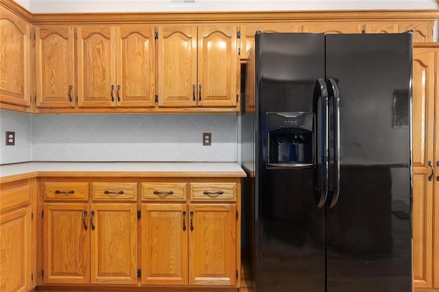kitchen featuring light countertops, black fridge with ice dispenser, and brown cabinets