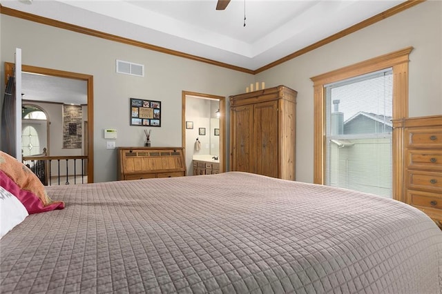 bedroom featuring a ceiling fan, visible vents, connected bathroom, ornamental molding, and a tray ceiling