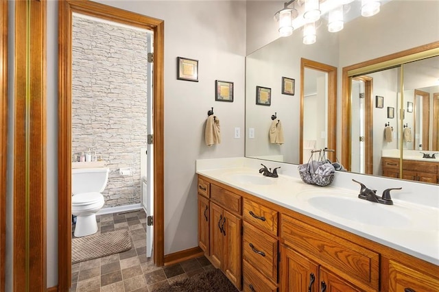 full bathroom featuring toilet, double vanity, baseboards, and a sink