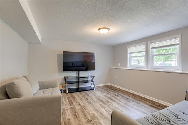 living area with wood finished floors, a textured ceiling, and baseboards