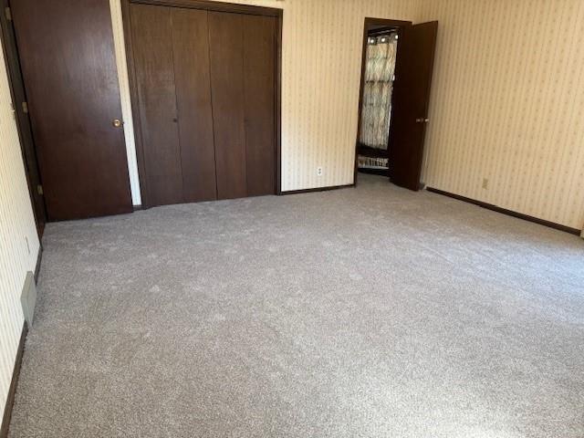 4926 Mockingbird Ln, Saint Joseph, MO 64506 - unfurnished bedroom featuring carpet flooring, wallpapered walls, and a closet