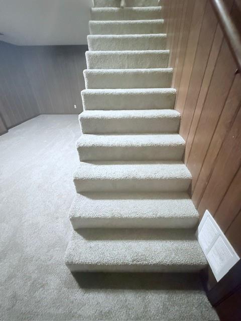 4926 Mockingbird Ln, Saint Joseph, MO 64506 - stairway featuring carpet flooring and wood walls