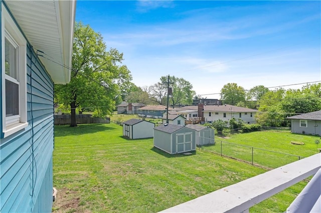 view of yard featuring a residential view, an outbuilding, a fenced backyard, and a storage unit