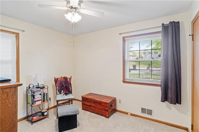 living area with carpet flooring, a ceiling fan, baseboards, and visible vents