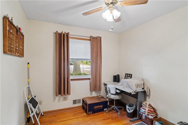 office space with baseboards, ceiling fan, light wood finished floors, and visible vents