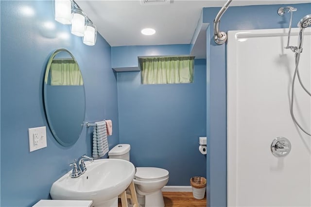 full bath with wood finished floors, toilet, baseboards, walk in shower, and a sink