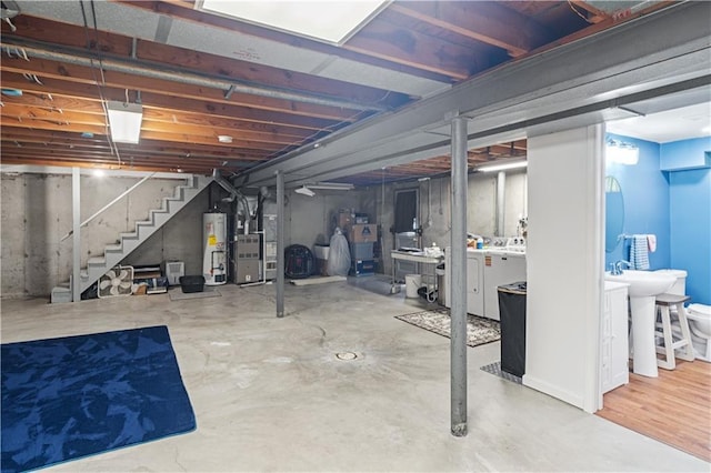 unfinished basement featuring a sink, water heater, stairs, heating unit, and washer and clothes dryer
