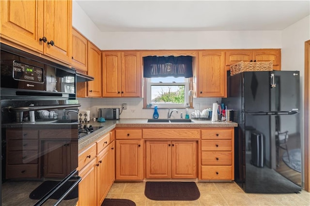 kitchen with tasteful backsplash, a sink, light countertops, black appliances, and under cabinet range hood