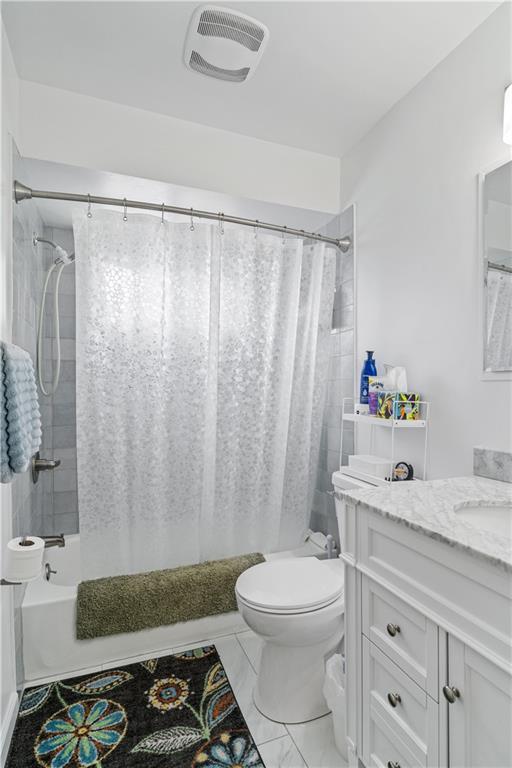 full bathroom featuring visible vents, vanity, toilet, marble finish floor, and shower / bath combo with shower curtain