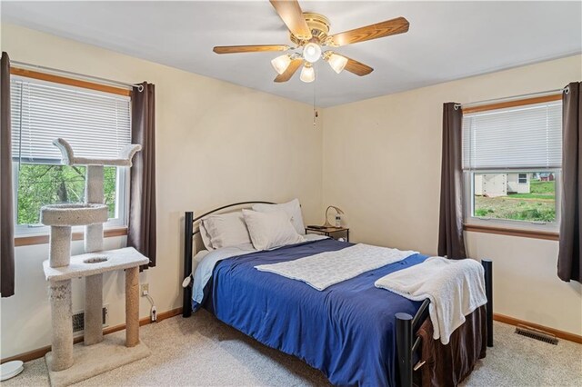 bedroom with baseboards, ceiling fan, light carpet, and visible vents