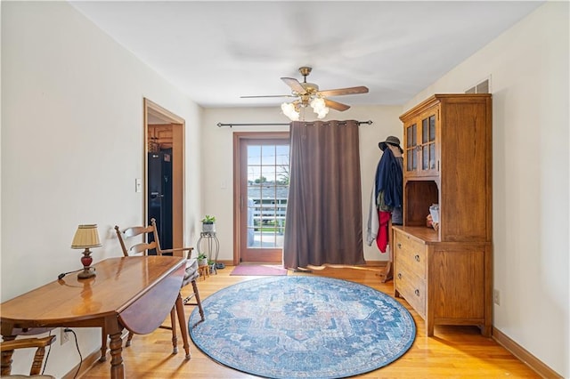 office space featuring baseboards, a ceiling fan, and light wood finished floors