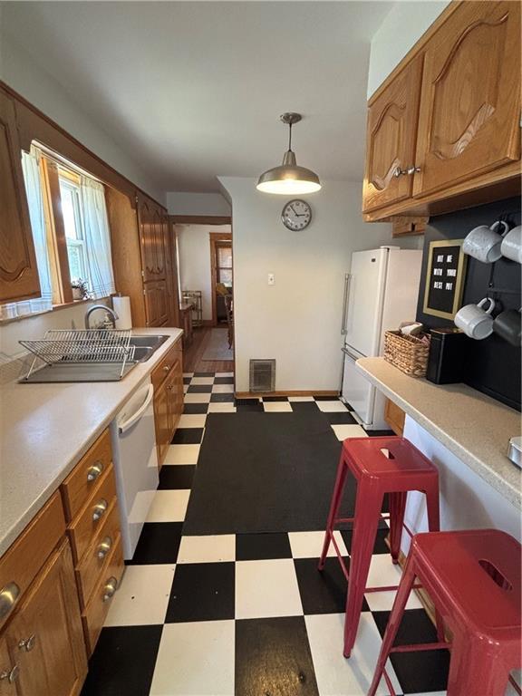 4019 Holly St, Kansas City, MO 64111 - kitchen with light flooring, freestanding refrigerator, brown cabinetry, and dishwashing machine